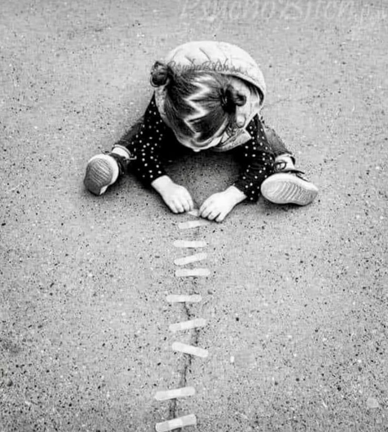 Child placing band-aid on cracked concrete